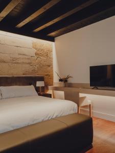 布里奥内斯Santa María Briones的一间卧室配有一张床和一张书桌及电视