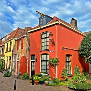 迪温特Atelier Raamwerk City Apartments Deventer 125m2!的庭院里一座橙色的房子,里面装有窗户和植物