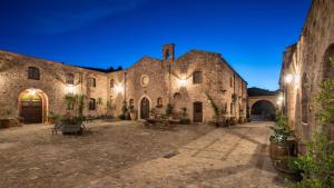 卡斯特布奥诺Relais Abbazia Santa Anastasia Resort & Winery的一座大型石头建筑,晚上有庭院