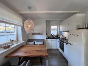 韦斯特兰To Huus - im Süden von Westerland的厨房配有木桌和白色冰箱。