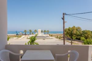 罗希姆诺Domenica Apartments的阳台配有桌子,享有海滩美景