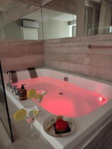 罗马il sogno di afrodite luxury b and b的浴室设有粉红色的浴缸、蛋糕和酒杯