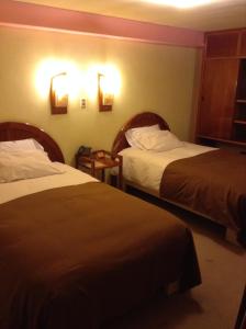 胡利亚卡Royal Inn Hotel Juliaca的酒店客房,设有两张床,墙上有灯