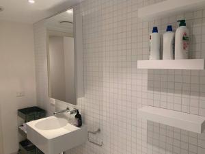 墨尔本Light-filled apartment in a dream location 150m away from University of Melbourne的白色瓷砖浴室设有水槽和镜子