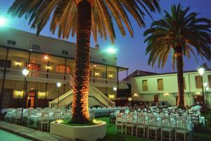 特鲁希略维多利亚酒店的一间设有桌椅的餐厅,种植了棕榈树