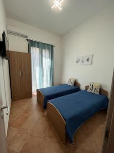 奇尼斯Sagra Vacanze Cinisi的一间卧室设有两张带蓝色床单的床和窗户。