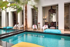 马拉喀什里亚德安塔拉旅馆的一个带椅子的游泳池以及一座房子