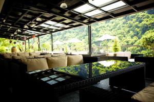乌来乌来Spring Spa温泉山庄的餐厅配有沙发和桌子,并设有大窗户。