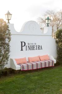 AlpiarçaQuinta da Pinheira Lezíria的坐在标牌前的草上的一个长凳