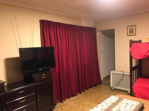 塔里哈Ballivian的一间带红色窗帘和电视的卧室