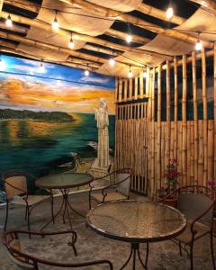 南圣胡安Tapihouse San Juan Del Sur的一间设有桌椅的房间和一幅雕像画