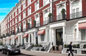 伦敦Heeton Concept Hotel - Kensington London的一个人在建筑物前的街道上行走