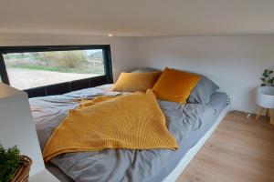 ElsflethWinzig Wohnen Tiny House Frigg direkt am Weserstrand的小房间的一个床位,配有黄色枕头