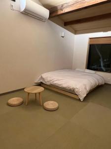 丰冈市城崎温泉 小宿 紬 tsumugi的一间卧室配有一张床、一张桌子和两张凳子
