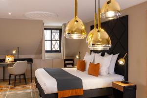 科尔马Hotel Le Colombier的酒店客房,配有一张金色灯床