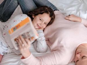 梅尔松根宜必思卡塞麦苏根酒店的躺在床上的小女孩和母亲一起读书