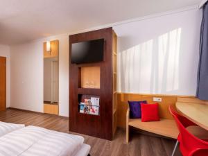 梅尔松根宜必思卡塞麦苏根酒店的卧室配有1张床、1张桌子和1把椅子