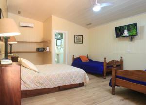 萨拉皮基Horquetas River Lodge的一间卧室设有两张床,墙上配有电视。