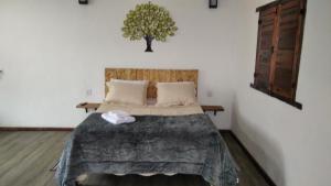 拉夫拉斯诺瓦斯Chalé Suite do chá的卧室配有一张床铺,墙上挂着一棵树
