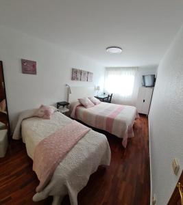 贝洛拉多Pension Toñi的一间卧室配有两张带粉色和白色床单的床