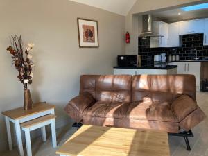 凯特林Garfield Cottage的客厅里一张棕色的皮沙发,配有桌子