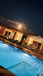 穆里吉奥尔Havana Resort的夜间游泳池,配有椅子和遮阳伞