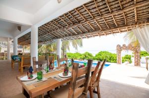 马特姆维Marafiki Beach Hotel & SPA的一间配备有桌椅的海景用餐室