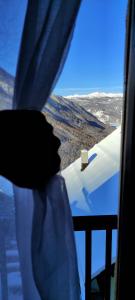Sauze di CesanaLa Grange的看到窗外白雪覆盖的山的人