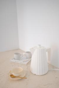 格里La Rose du Cèdre的一张带两个杯子的桌子上的白色花瓶