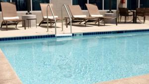 德卢斯Sonesta Select Atlanta Duluth的大楼内一个带椅子和桌子的游泳池