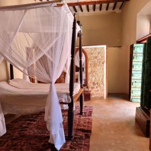 莫桑比克岛Terraço das Quitandas Design Accommodation-AL的一间卧室配有带蚊帐的天蓬床。