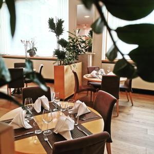 卢布尔雅那卢布尔雅那城市酒店的餐厅设有桌椅、眼镜和餐巾