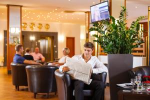 拜罗伊特莱茵黄金酒店的坐在椅子上看报纸的人