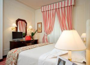 佛罗伦萨德拉维勒酒店的酒店客房配有床、灯和镜子