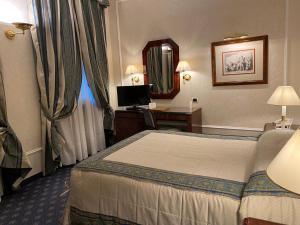 佛罗伦萨德拉维勒酒店的酒店客房带一张床、一张书桌和一面镜子