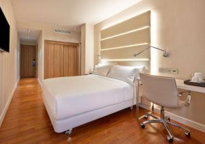 巴塞罗那巴塞罗那勒哥尔特NH酒店的卧室配有白色的床、书桌和椅子