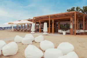 维耶斯泰皮佐穆诺维斯特宫酒店的海滩上的一座建筑,配有白色的椅子和遮阳伞