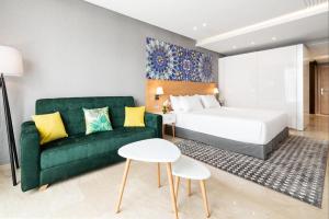 卡萨布兰卡Mid Town Hotel Casablanca的酒店客房,设有一张床铺和一张绿色沙发