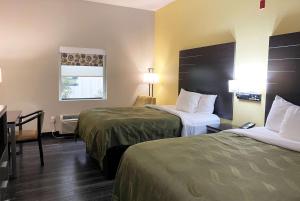 比洛克西Wingate by Wyndham Biloxi - Ocean Springs的酒店客房设有两张床和一张桌子。