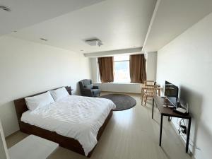 仁川市Incheon Airport Guesthouse的一间卧室配有一张床、一张书桌和一台电视