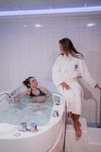卡罗维发利Hotel Thermal的站在男人旁边浴缸中的女人
