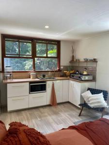 库兰达Tranquil Rainforest Studio Kuranda的厨房配有白色橱柜、水槽和窗户。