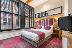 曼彻斯特曼切斯特市罗姆兹酒店的一间卧室配有一张床和一台平面电视