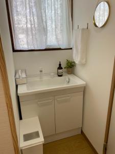 日向ゲストハウスHINATA的浴室设有白色水槽和镜子