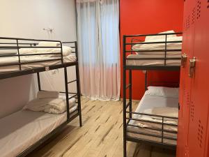 米兰QUO Milano的客房设有两张双层床和红色的墙壁。