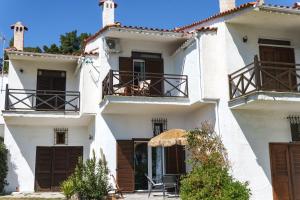 波塞蒂Delfini Villa, beachfront 2-bdrm maisonette的白色的房子,窗户上有棕色百叶窗