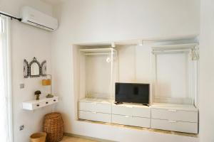 波塞蒂Delfini Villa, beachfront 2-bdrm maisonette的一间客厅,客厅的白色橱柜上配有电视