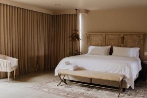 瓜塔佩Tau House的卧室配有一张白色大床和一把椅子