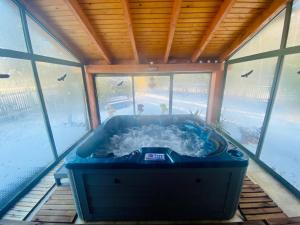 RybakiWilla Siemianówka - Sauna, Jacuzzi的窗户客房内的大蓝色浴缸