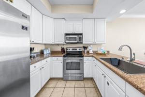 格尔夫海岸San Carlos Unit 607的厨房配有白色橱柜和不锈钢用具